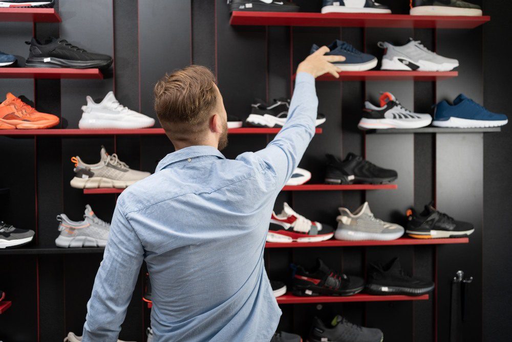 hombre escoge calzado en tienda de zapatos